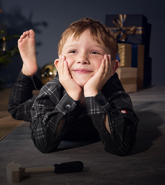 Un jeune homme portent le pyjama à carreaux e.s. dans un salon décoré pour Noël